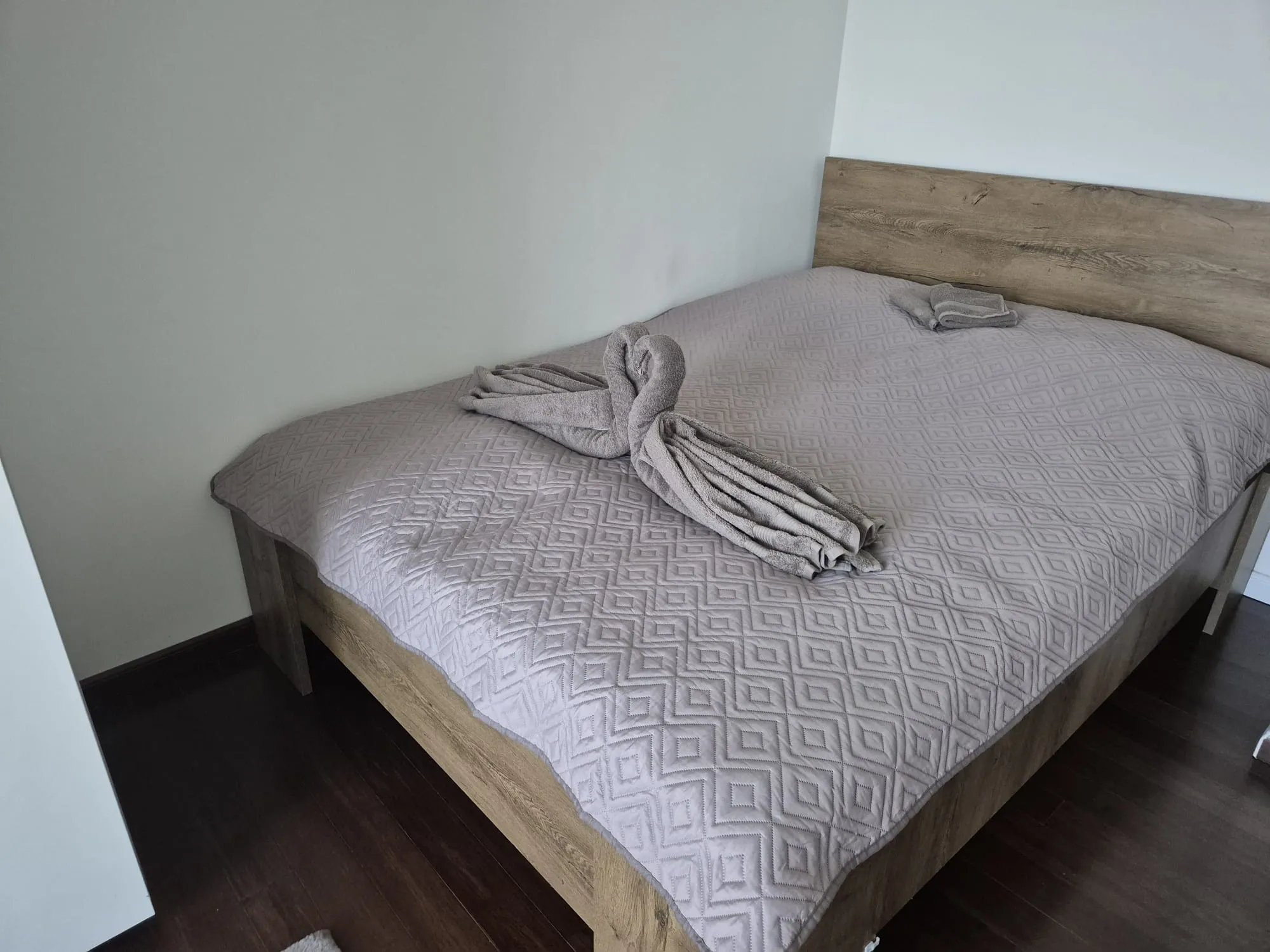 Povlečená postel s ručníky složenými do tvaru labutě